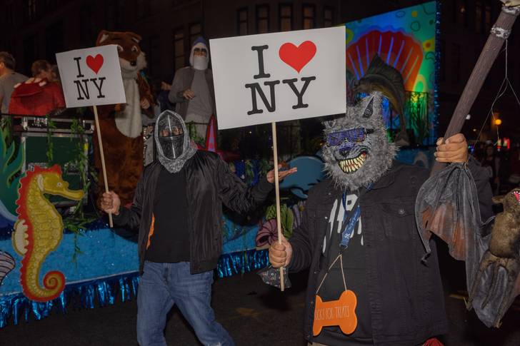 People wearing Halloween costumes, holding up signs.